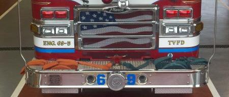 A firetruck in front of the fire department emblem on the floor of the firehouse