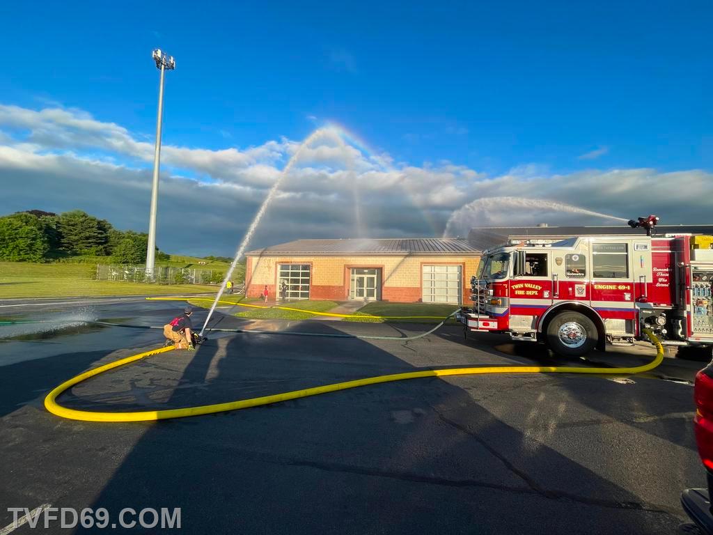 Using the hose on a firetruck to spray the roof of a building