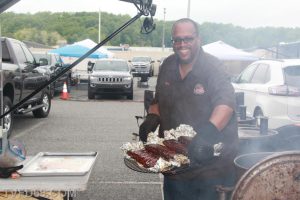 A man smiling while holding a tray of cooked meat