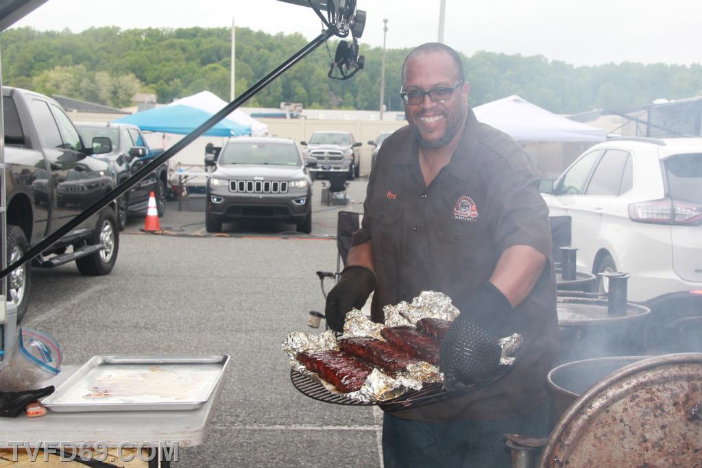 A man smiling while holding a tray of cooked meat